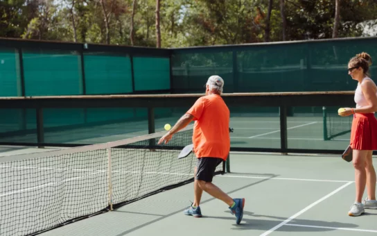 Man playing tennis with orange shirt