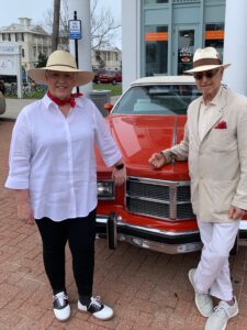 pam avera and robert davis standing in front of a red car