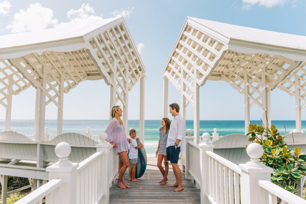 Family standing on a beach boardwalk gazebo overlooking the ocean on a sunny day.